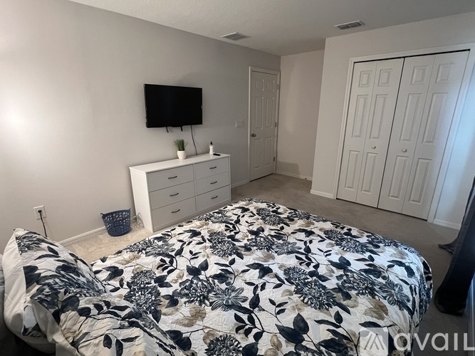 A bedroom with a bed, dresser, and TV.