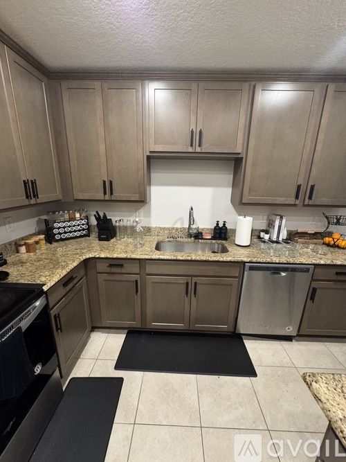 A kitchen with a black stove top oven and a black mat on the floor.