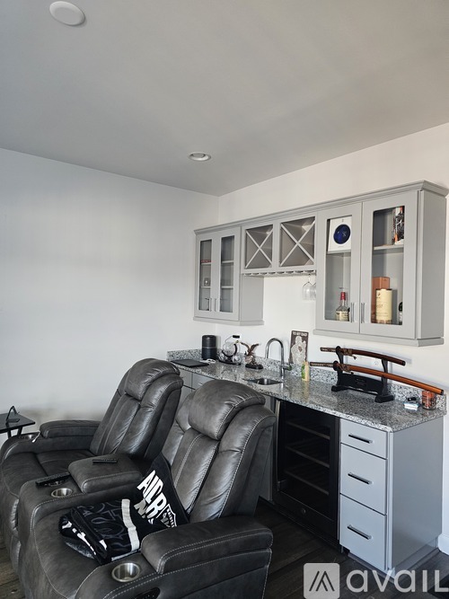 A black leather recliner chair is in front of a kitchen island with a sink and a counter.