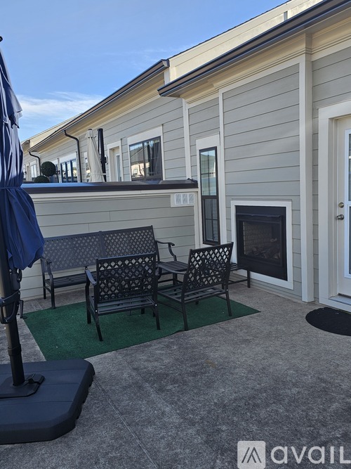 A patio with a table and chairs and a blue umbrella.