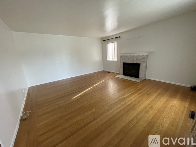 A room with wooden flooring and a fireplace.