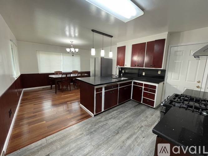 A kitchen with a black countertop and wooden flooring.