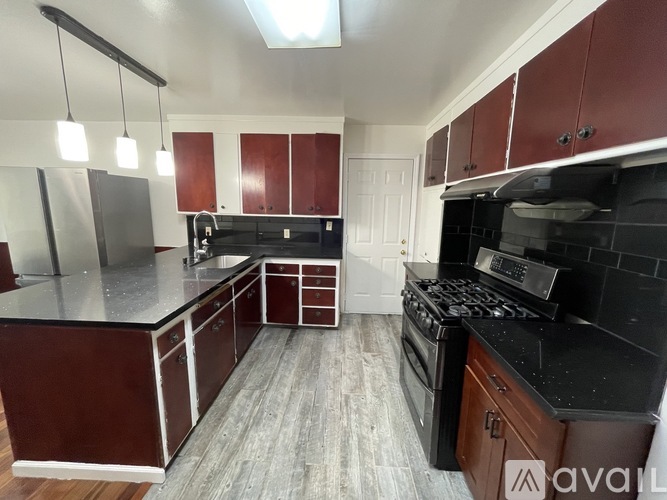 A kitchen with dark wood cabinets and black countertops.