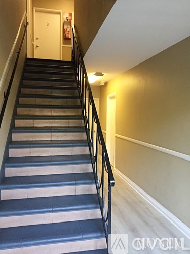 A staircase with a black railing and a white door at the top.