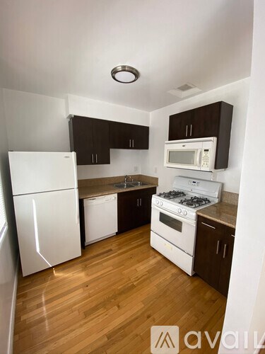 A kitchen with white appliances and brown cabinets.