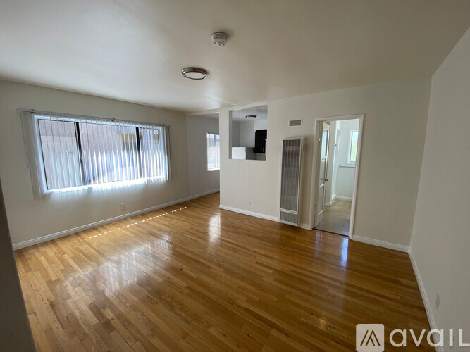 A spacious room with wooden flooring and a large window.