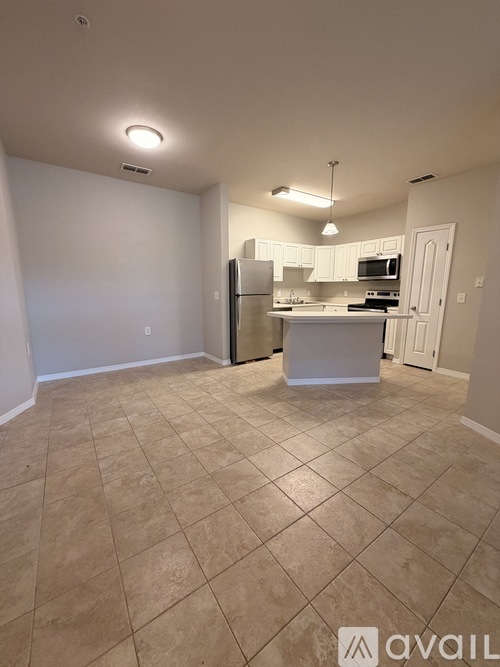 A kitchen area with tile flooring and a refrigerator.