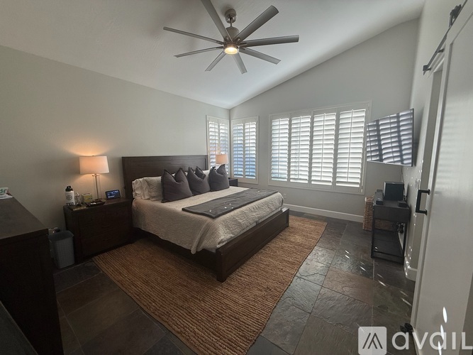 A bedroom with a large bed and a ceiling fan.