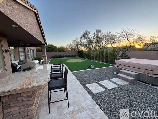 A patio with a table and chairs overlooks a backyard with a lawn and trees.