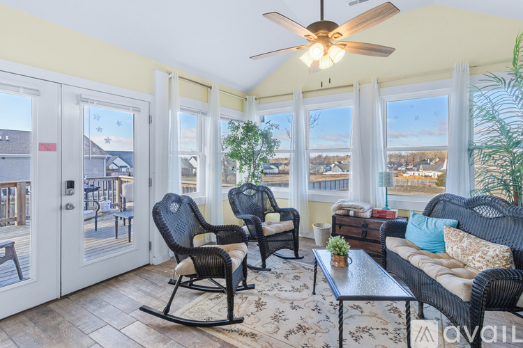 A sunny day view from a living room with a rocking chair and a sofa.