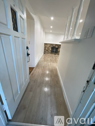 A hallway with wooden floors and white walls.