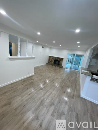 A spacious room with wooden flooring and a fireplace.