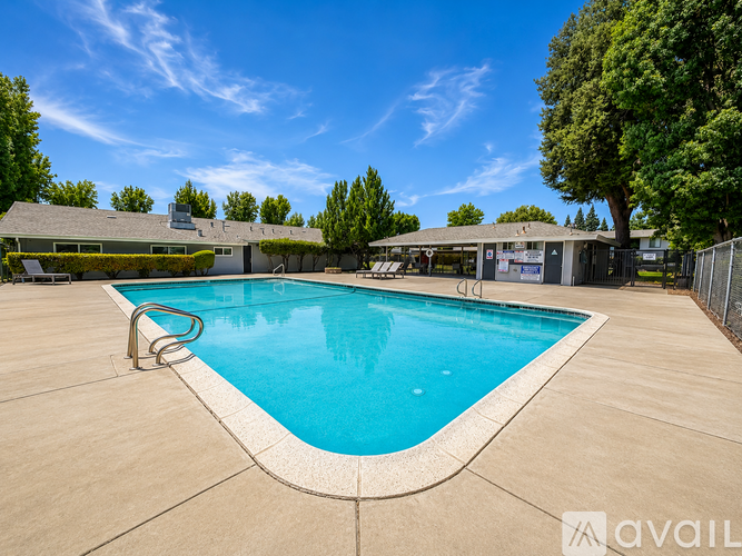 A swimming pool surrounded by a concrete patio and a fence.