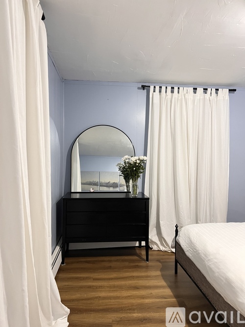 A bedroom with a bed, a dresser with a mirror, and a vase of flowers.