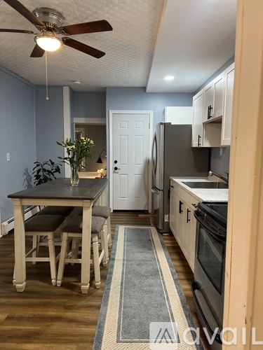 A kitchen with a table and chairs in front of a refrigerator.