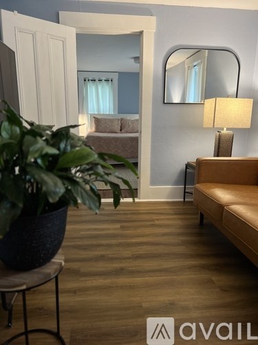 A living room with a brown sofa and a potted plant on a table.