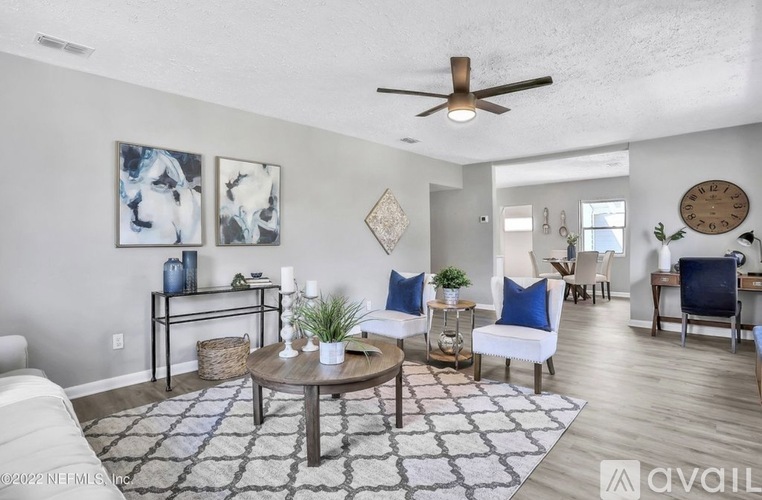 A living room with a white couch, a coffee table, and a ceiling fan.
