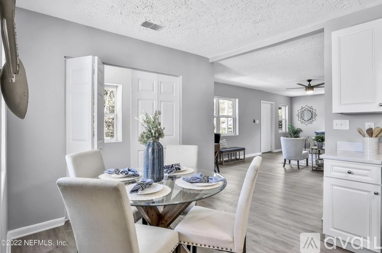 A well-lit, spacious dining area with a glass table and white chairs.