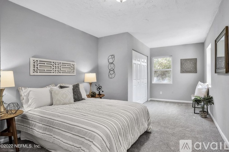 A bedroom with a bed, two lamps, and a mirror on the wall.