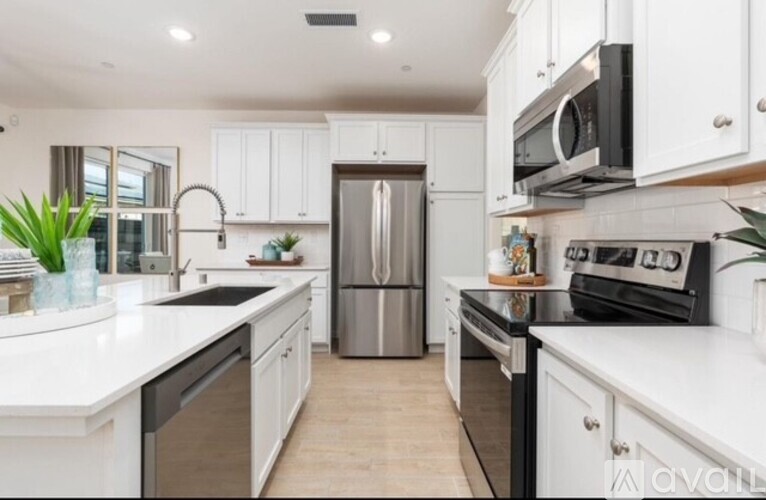A modern kitchen with white cabinets and stainless steel appliances.