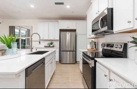 A modern kitchen with white cabinets and stainless steel appliances.
