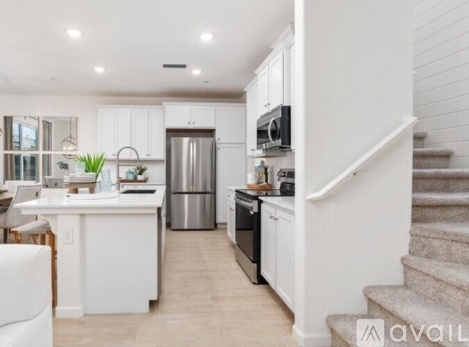 A modern kitchen with white cabinets and stainless steel appliances.