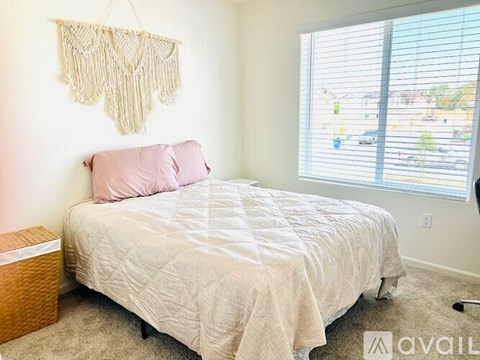 A bedroom with a bed, pillow, and a macrame hanging on the wall.