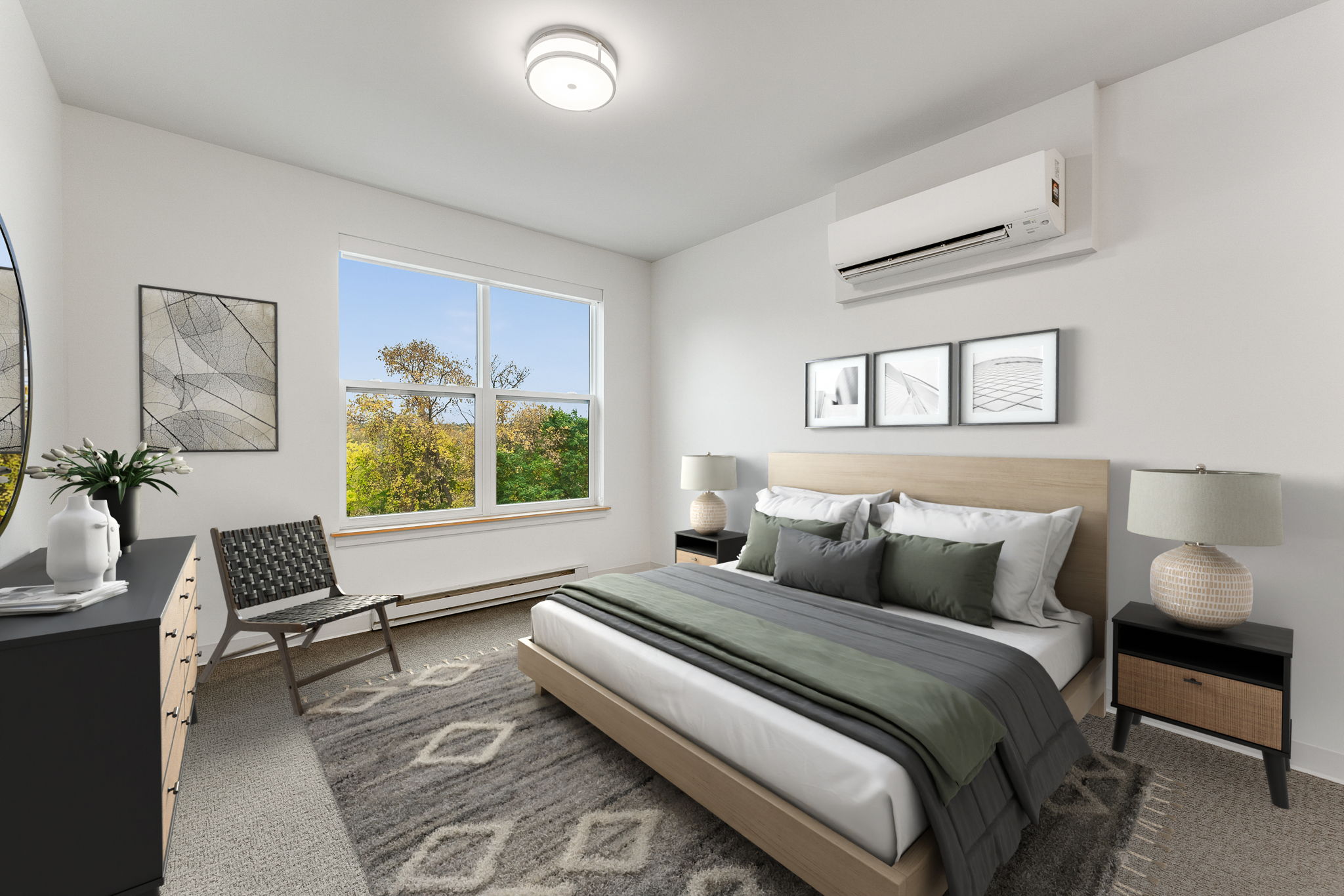 A well-lit bedroom with a large bed and a view of trees outside the window.