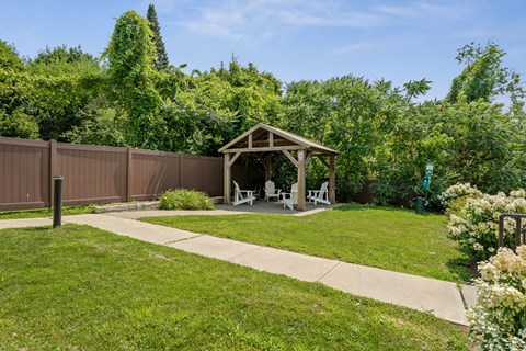 A backyard with a wooden gazebo and a fence.