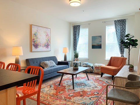 A living room with a grey couch, a red chair, a black table, and a painting on the wall.