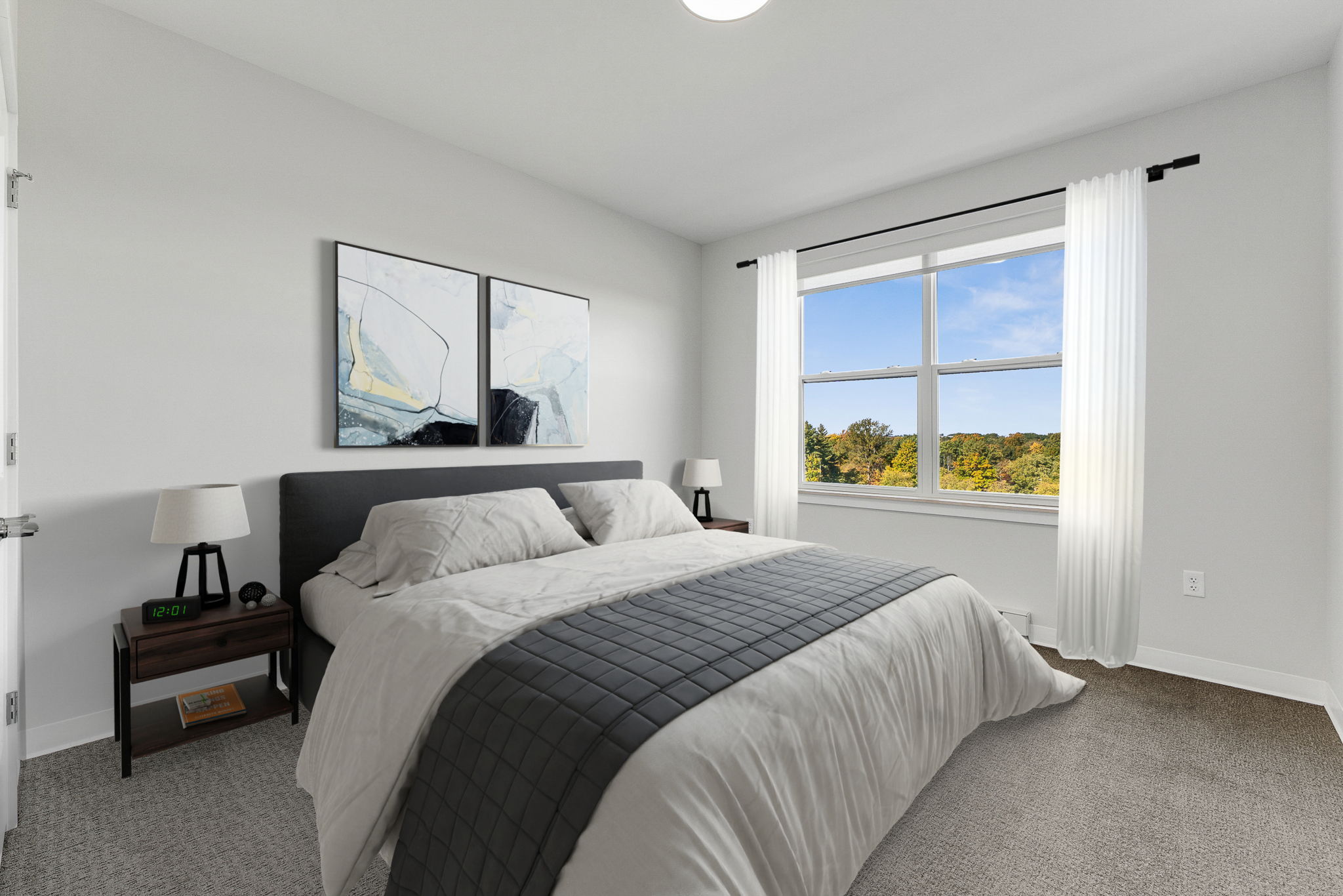 A bedroom with a large bed and a window overlooking the trees.