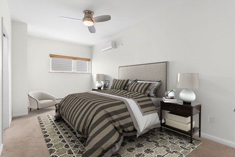 A bedroom with a bed, chair, and ceiling fan.
