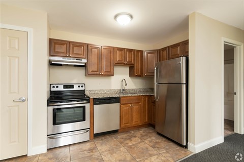 A kitchen with a stove, oven, refrigerator, and cabinets.