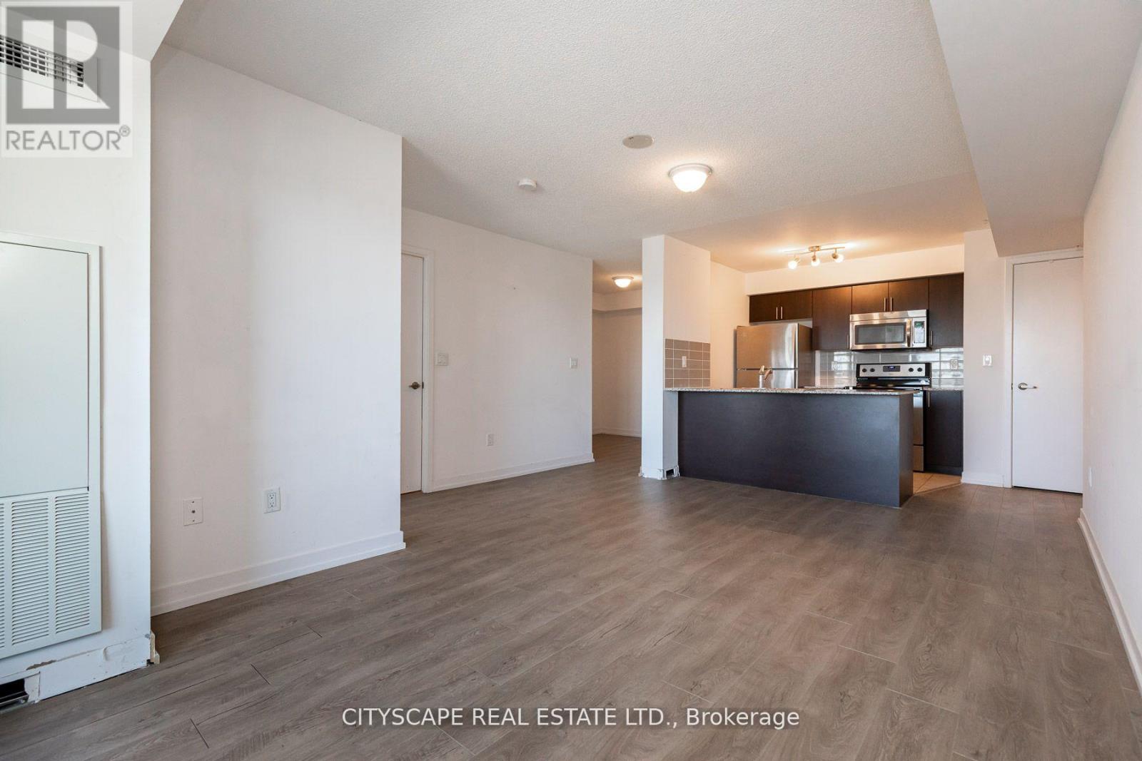 A spacious living room with a kitchenette in the background.