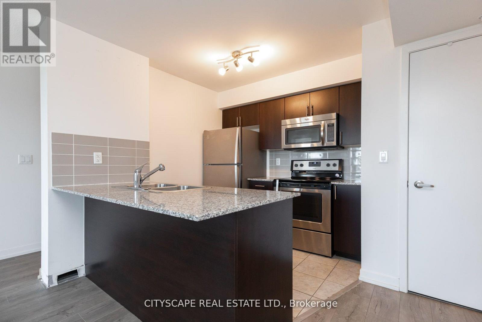 A kitchen with a granite countertop and stainless steel appliances.