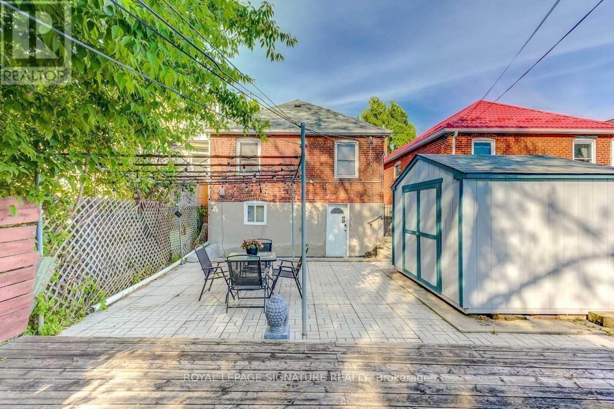 A backyard with a table and chairs is surrounded by a fence and a brick building.