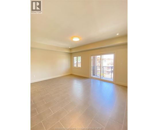 A spacious room with tile flooring and a large window.