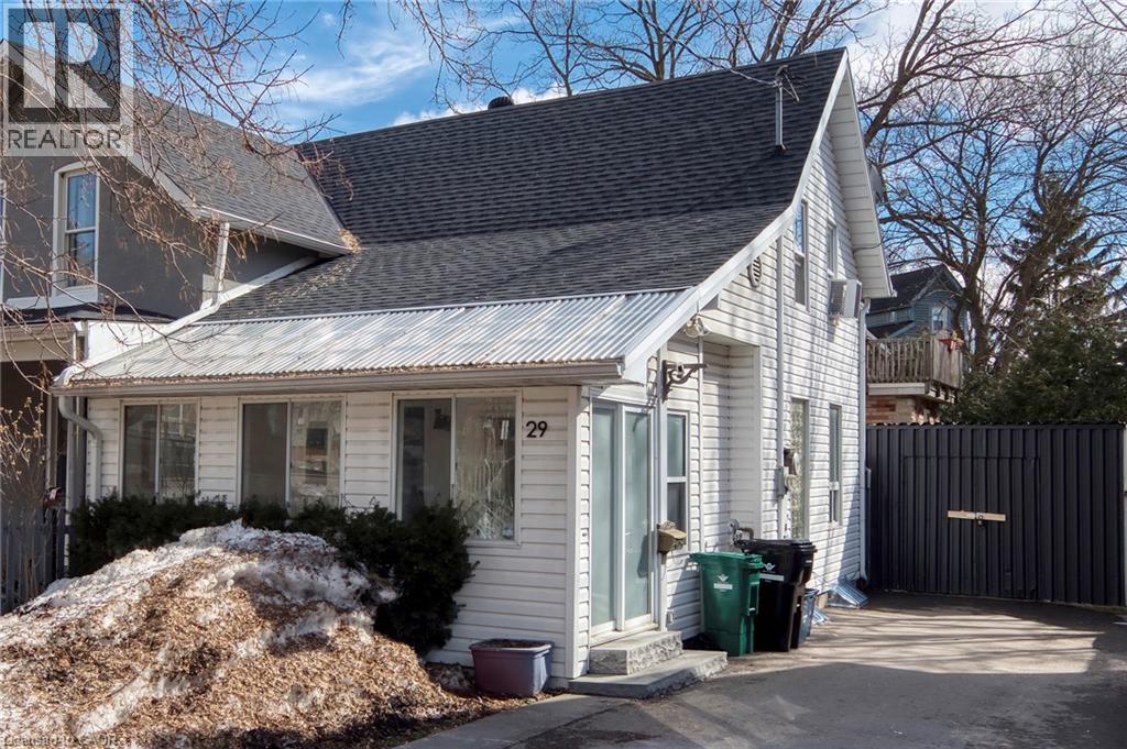 A white house with a black roof and a sign that says REALTOR.