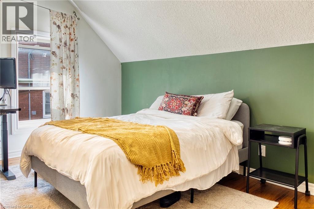 A bedroom with a bed covered in a white comforter and a yellow throw.