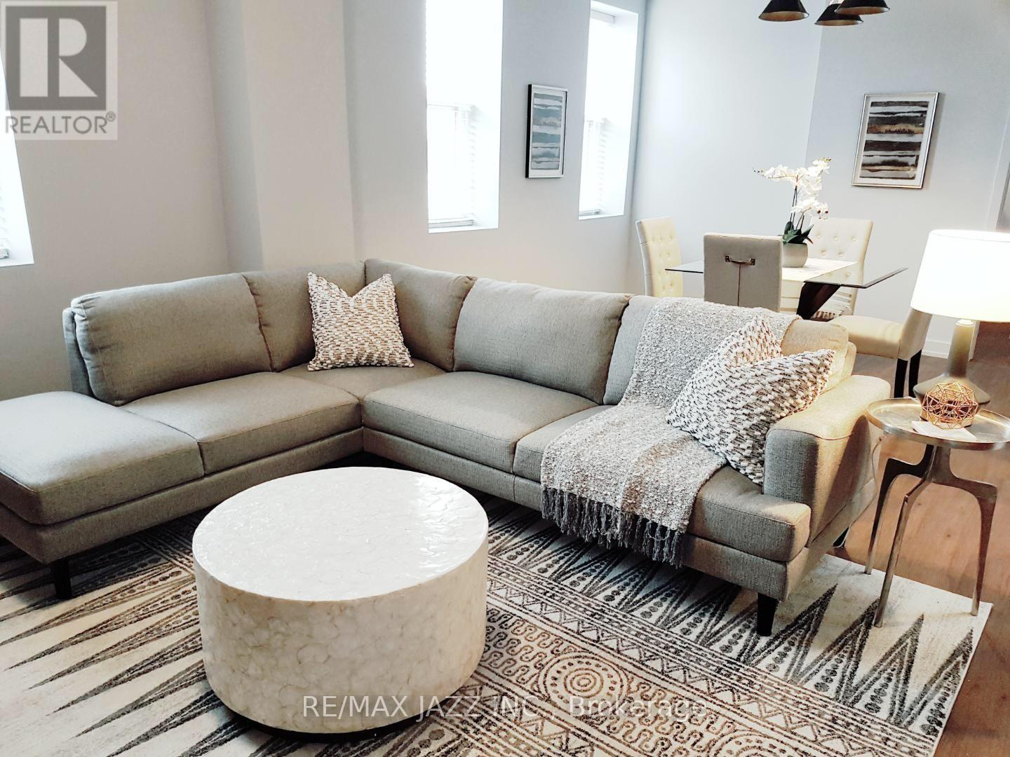 A living room with a grey couch and a white ottoman.