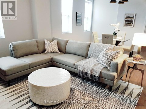 A living room with a grey couch and a white ottoman.