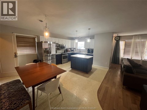 A well-lit kitchen and dining area with a wooden table and chairs.