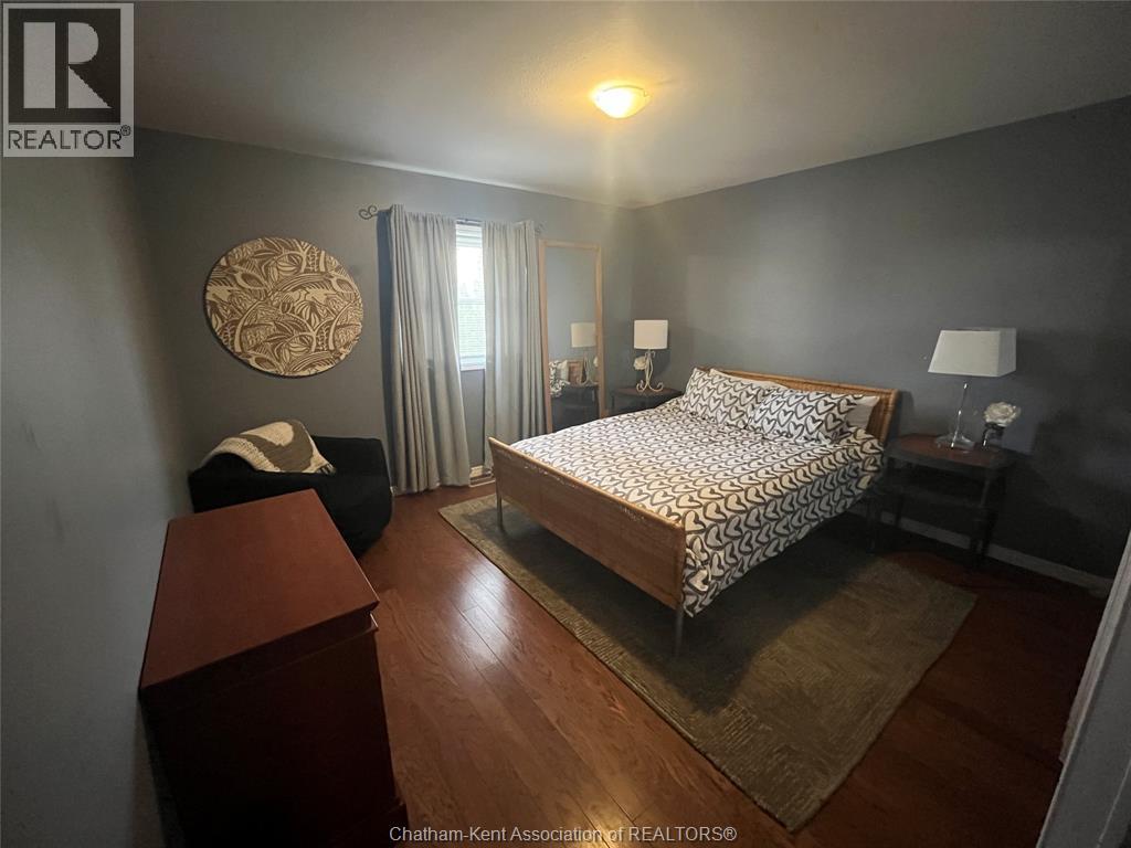 A bedroom with a bed, nightstand, and chair.