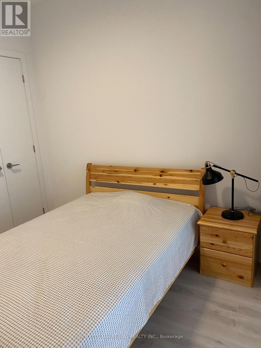 A bedroom with a bed, nightstand, and lamp.