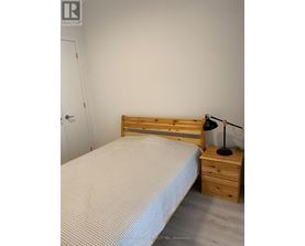 A bedroom with a bed, nightstand, and lamp.