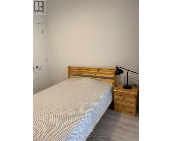 A bedroom with a bed, nightstand, and lamp.