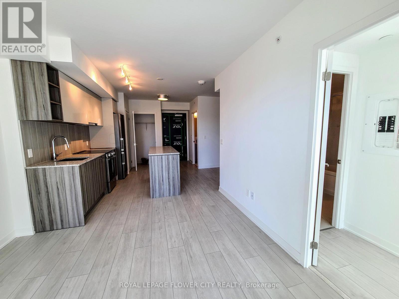 A spacious room with a kitchen area and a doorway leading to another room.