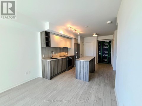A modern kitchen with a wooden island and a refrigerator in the background.