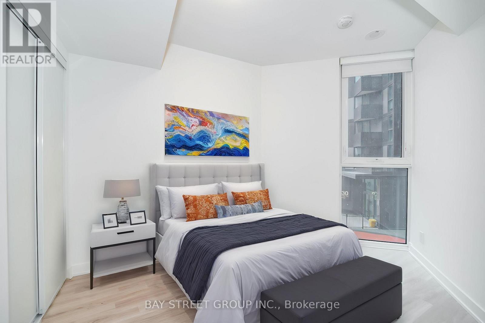 A bedroom with a large bed and a painting on the wall.