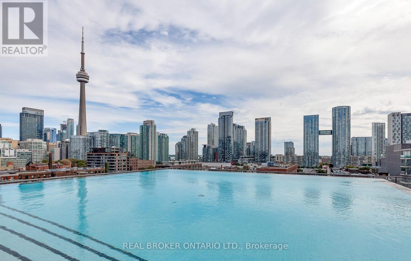 A cityscape with a large pool in the foreground and the CN Tower in the background.